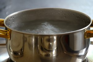 Metal pan on stove boiling water.