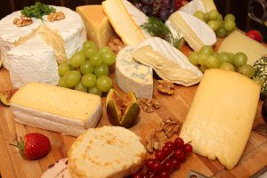 Assorted cheeses on a board with grapes.