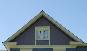 Close up of gabled ends, molded cornice, paired single like windows.