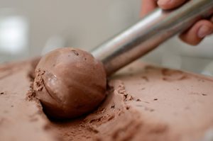 Chocolate ice cream being scooped out of the container.
