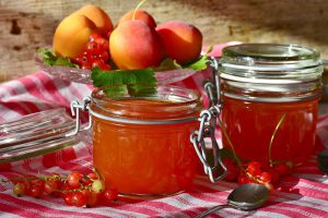 Apricot around 2 jam jars filled with apricot homemade jam.