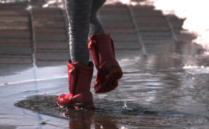 Red boots playing in a puddle.