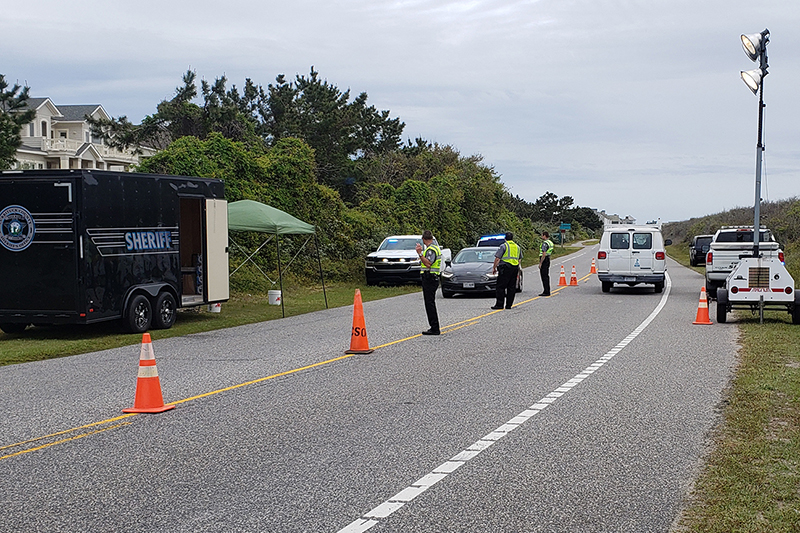 Re-entry checkpoint in Corolla. Several Sheriff Deputies with cars and the Sheriff's trailer.