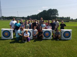 Teens and staff standing behind archery targets.