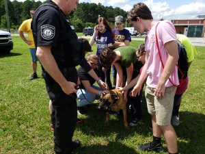Teens petting the one of the K-9 dogs with his handler.
