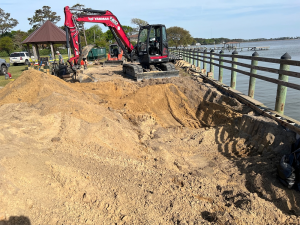 Heavy equipment moving dirt along the water edge.