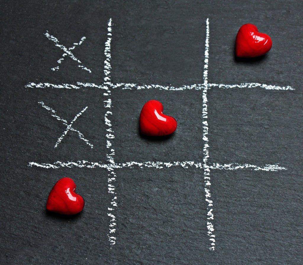 Tic-Tac-Toe game on a black background with 3 red hearts in a row.