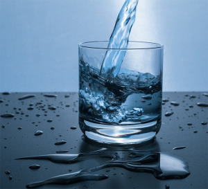 Water pouring into glass on a blue background.